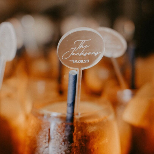Row of orange cocktails with straws and 'The Jackson' sign in a blurred bar setting
