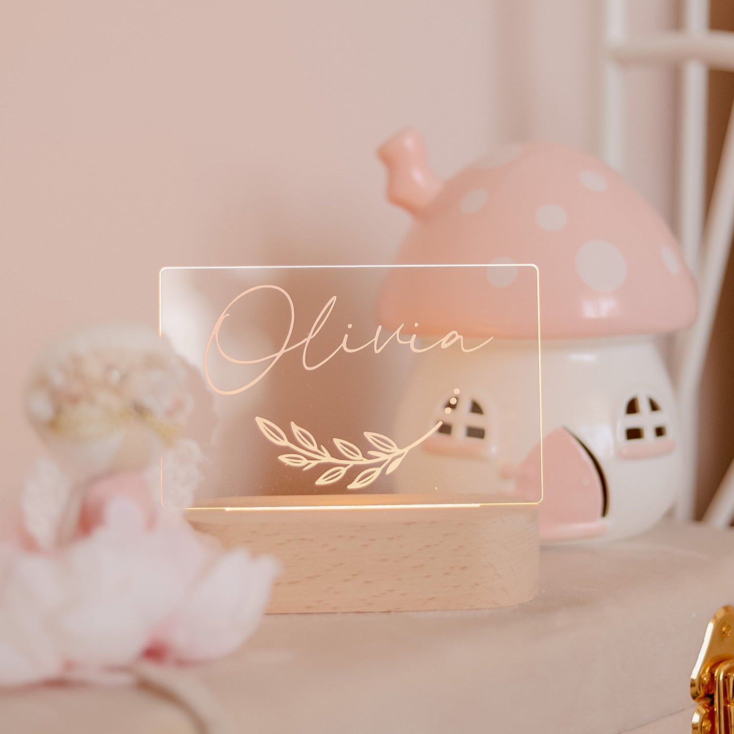 Decorative nameplate with 'Olivia' and a leaf design on a wooden base, blurred background